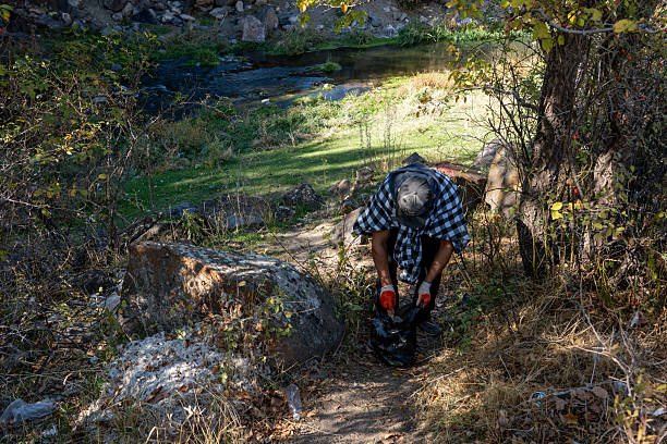 Man Collecting Litter in a Forest Park During Fall – Environmental Awareness and Volunteering