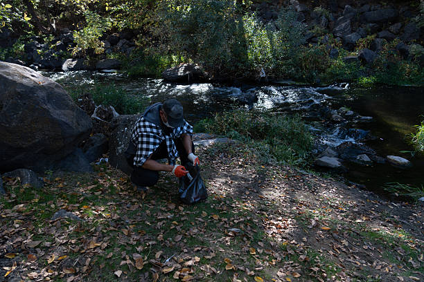 Man Collecting Litter in a Forest Park During Fall – Environmental Awareness and Volunteering