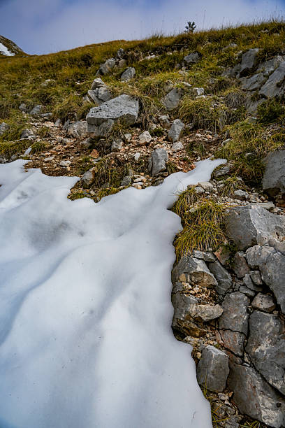 istock Rocky hill with grass partially covered in snow 2242388912