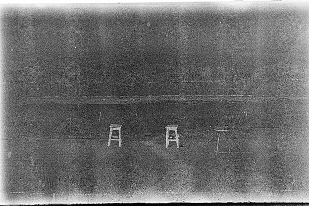 Abstract black and white photograph showing a rough, weathered surface with visible film grain and texture.