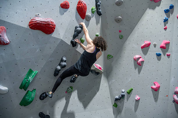 istock Climber On Indoor Bouldering Wall Doing Roof Move 2242400020