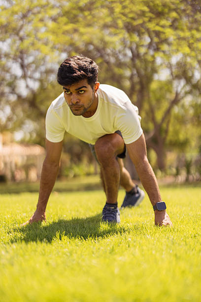 istock Athlete in a starting crouch on a sunny park lawn during outdoor training session 2242400025