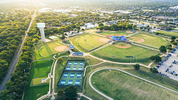 istock Grassy meadow, rail track borders, curved concrete path, busy surface parking. Park sports fields, water tower ideal for family recreation, large-scale community events in Highland Village, Texas 2242400570