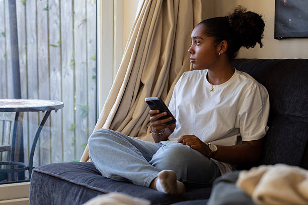 istock Young Woman Sitting on Sofa and Looking Thoughtfully Out the Window 2242402555