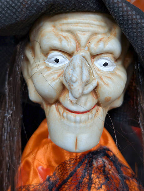 istock Creepy witch doll with exaggerated features and a dark hat displayed in a Halloween themed setting 2242403408