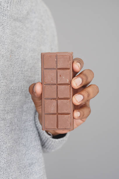 istock Holding a chocolate bar with a gray sweater background 2242407540