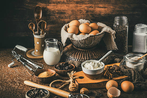 Variety of baking ingredients on rustic bronw table. Preparation for home baking.