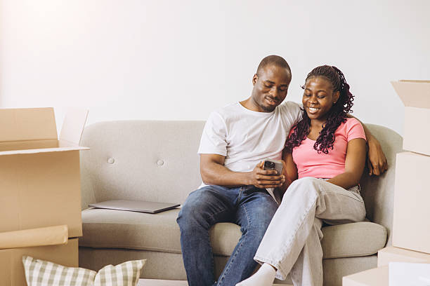istock African couple relaxing on couch with phone during moving day 2242410067