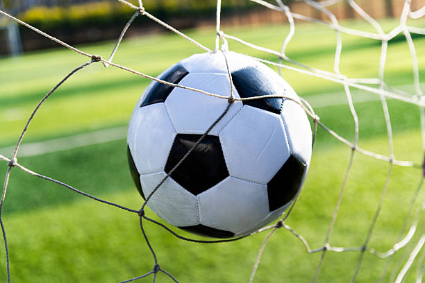 Soccer ball in goal net with grass background