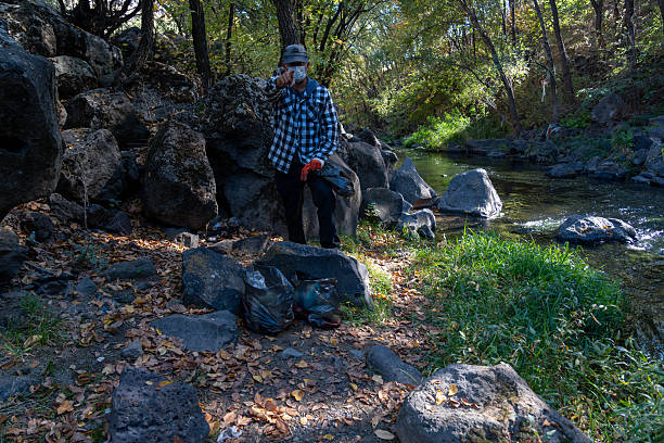 Man Looking at Camera with Trash Bags in Nature – Environmental Responsibility and Anti-Littering Message