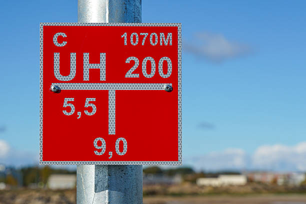Close-up of a red reflective fire hydrant location information sign mounted on a galvanized metal pole against a bright blue sky background