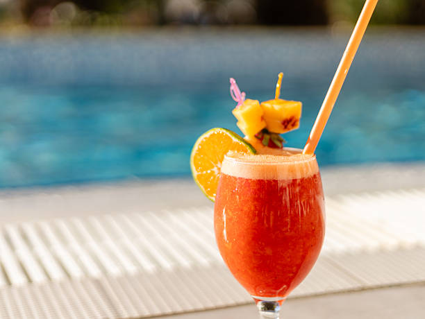 istock A colorful cocktail garnished with orange and pineapple sits on a table by a shimmering pool under the warm sun. Ideal for relaxation and enjoyment 2242414557