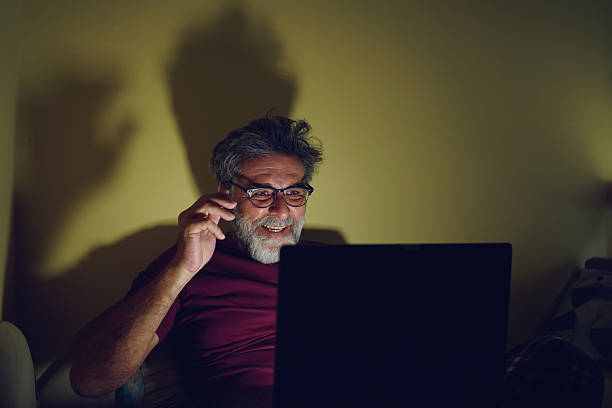 istock Senior man using laptop in bed at night, watching entertaining content 2242416727