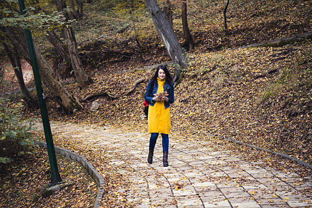 Woman enjoying relaxing walk in colorful autumn forest foothpath