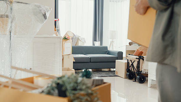 Young Asian couple help each other moving carton box full of stuff get some rest sit on sofa couch in living room at new house. Husband and wife move new house, Apartment Rent And Ownership Concept.