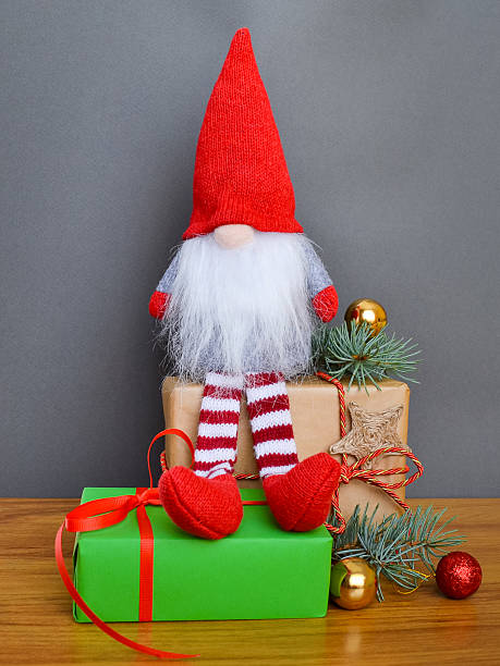 istock Christmas composition with a gnome sitting on a gift on a gray background 2242425385