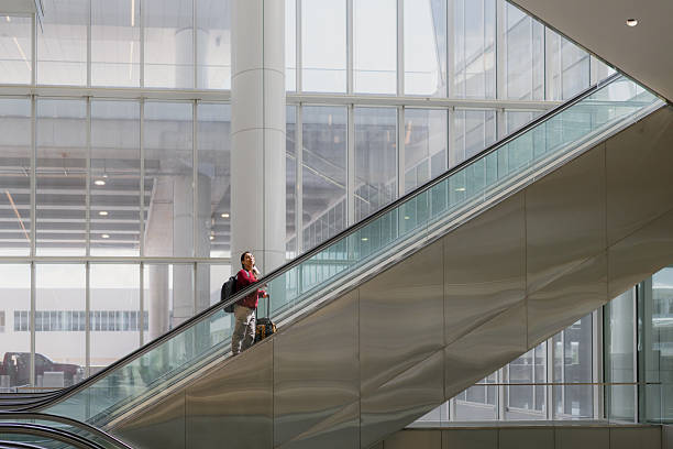 istock Traveler ascending escalator in bright modern airport terminal 2242427054
