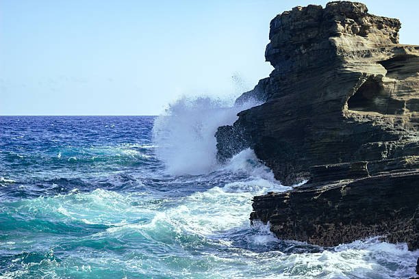 istock Ocean wave crashing against cliffs under the clear blue sky 2242428949