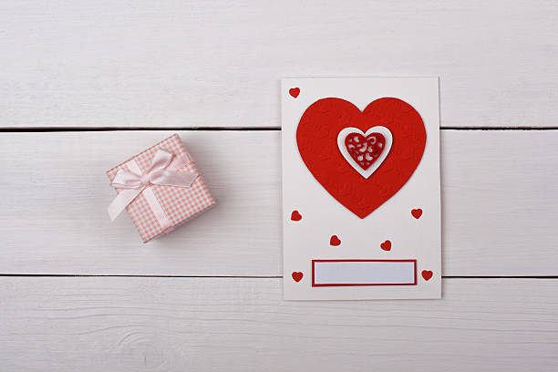 A gift and a card with red hearts on the table.