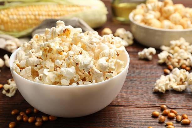 istock Tasty popcorn, corncob and corn kernels on wooden table, closeup 2242430282
