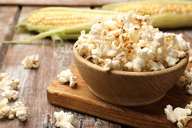 istock Tasty popcorn and corncobs on wooden table, closeup. Space for text 2242430353