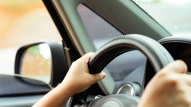 istock Person driving car, hands on steering wheel 2242434329