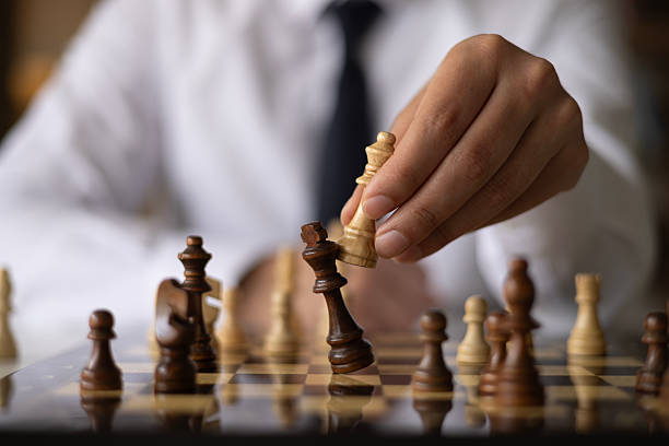 istock Businessman moving chess piece on chess board game 2242439624