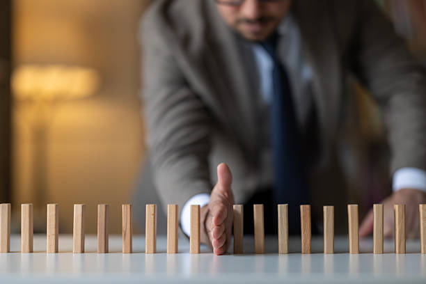 Businessman Stop Domino Effect. Risk Management and Insurance Concept