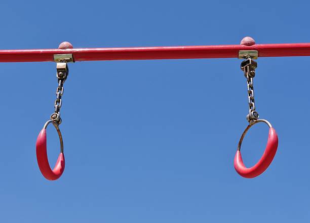 Cute little boy having fun playing at an outdoor backyard playground, climbing and swinging on gymnastics rings
