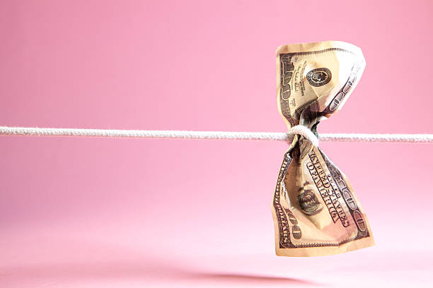 istock Dollars hanging on a clothesline on a pink background. 2242445599