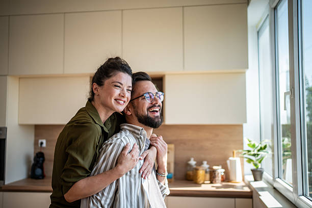 istock Happy couple embracing in modern kitchen with sunlight 2242448041