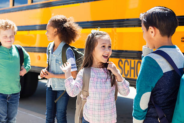 istock Children with backpacks excited about school while standing near a yellow bus 2242449593