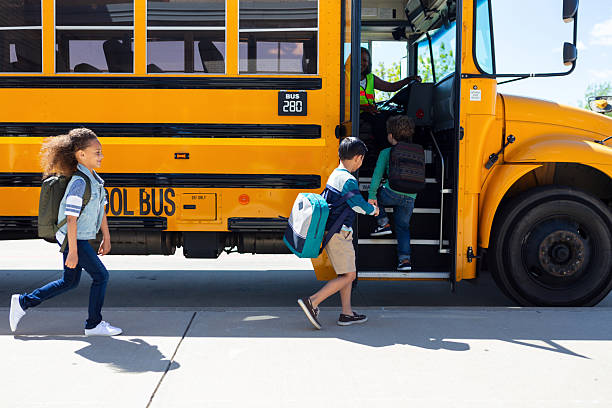 istock Children and driver boarding a bright yellow school bus on a sunny day. 2242449598