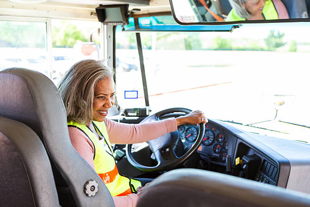 istock Experienced woman drives a bus with a cheerful expression, holding the steering wheel confidently. 2242449614