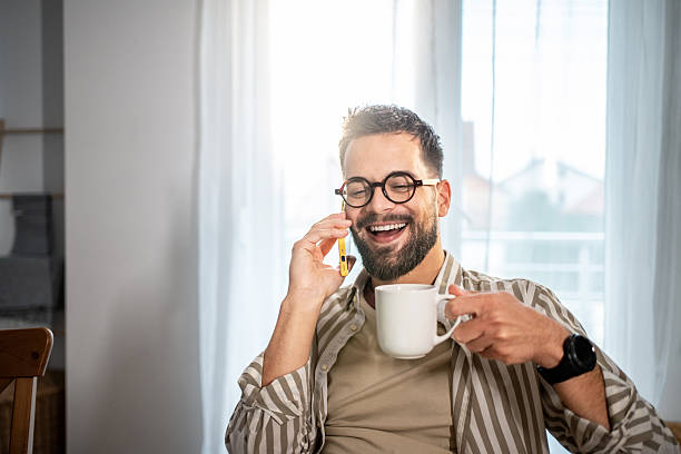 istock Happy man talking on phone and drinking coffee at home 2242454895