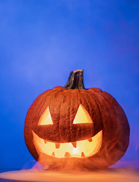 Creepy Halloween Pumpkin with Glowing Red Eyes and Smoke on blue background