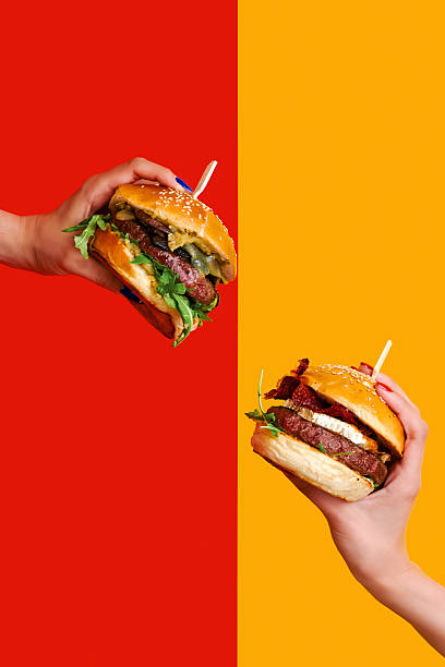 istock Two Hands Holding Burgers 2242457937