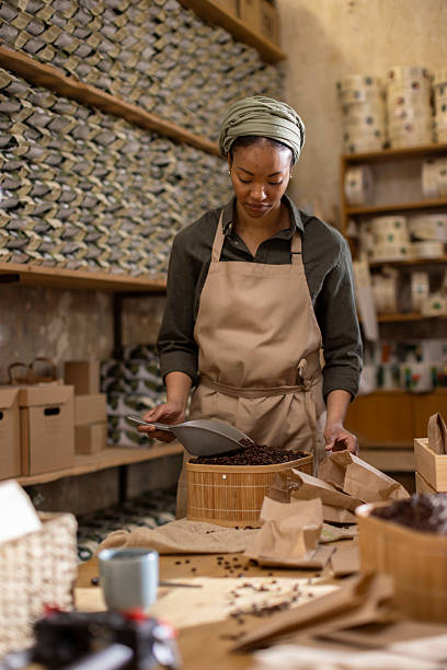 istock Female Artisan Roaster In Apron Scooping Coffee Beans In Rustic Workshop Setting Behind Sacks of Beans 2242459560