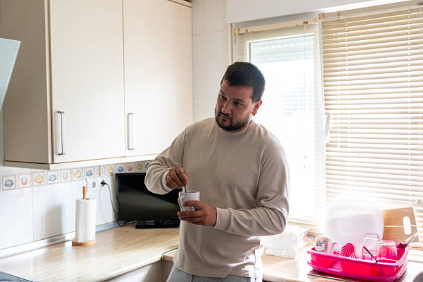 istock Man stirring coffee in kitchen during morning routine at home, enjoying a relaxed breakfast moment 2242459676