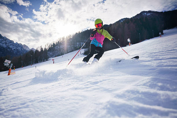 Young woman skiing in bright colorful ski gear on a mountain slope in winter.