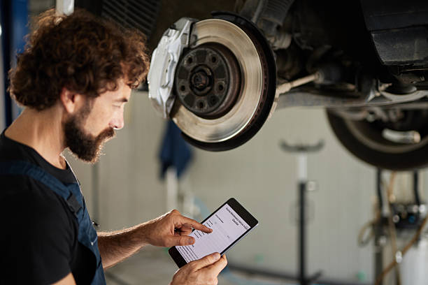 istock Car mechanic inspecting brakes using digital tablet in auto repair shop 2242462964
