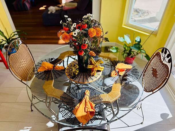 Beautiful shape of pumpkins on dinning table arrangement. Star like pumpkin and vase of colorful flowers (yellow, orange, red, green, purple, black). It is a round table with four chairs arranged for a special occasion. Unique design. Located in Corona, California.