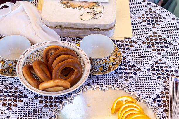 A charming outdoor still life with traditional turkish bagels, golden tea cups and a vintage wooden box on a lace tablecloth