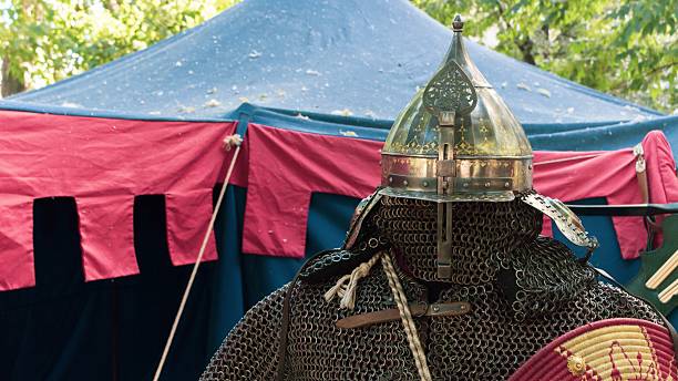 istock A historical reenactor wearing authentic medieval armor stands near a blue and red tent during an outdoor festival 2242469067