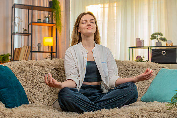 istock Woman meditating peacefully on home sofa, calm expression, eyes closed, relaxation, taking a break 2242470731