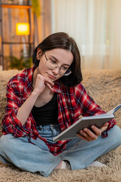 istock Young woman reading old journal notebook at home, smiling thoughtfully with soft nostalgic emotion 2242470759