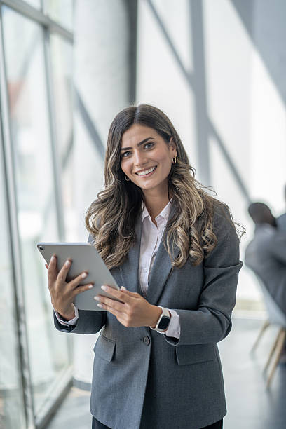 istock Young businesswoman smiling and using digital tablet in modern office 2242470820