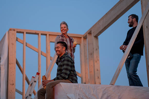 istock Friends Building A Frame At Sunset: Teamwork On A Wood-Frame Construction Site 2242471012
