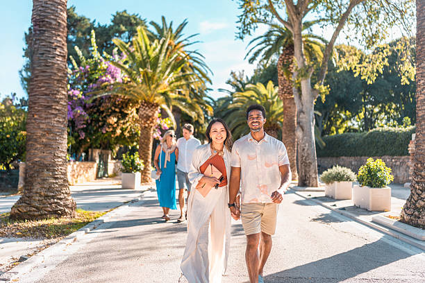 istock Diverse Couples Strolling Sunny Palm Promenade 2242471852
