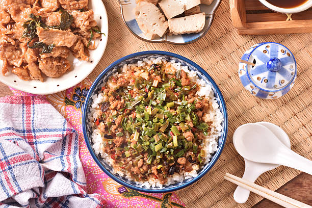 Fried minced pork with chive flower and black bean sauce over rice on wood table
